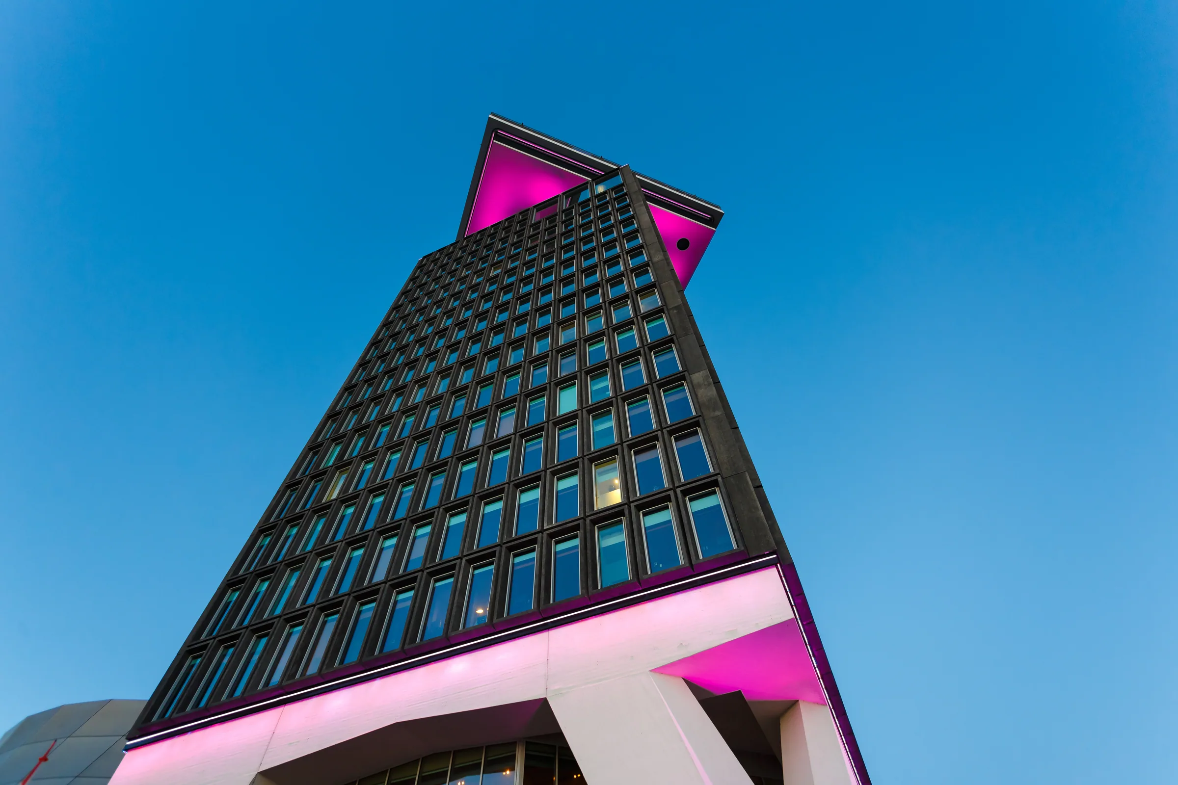 Amsterdam nightlife neighborhoods — the A'DAM tower in Noord lit magenta at dusk, the block above Shelter, the one high-traffic club that sits outside the Centrum and Rembrandtplein core