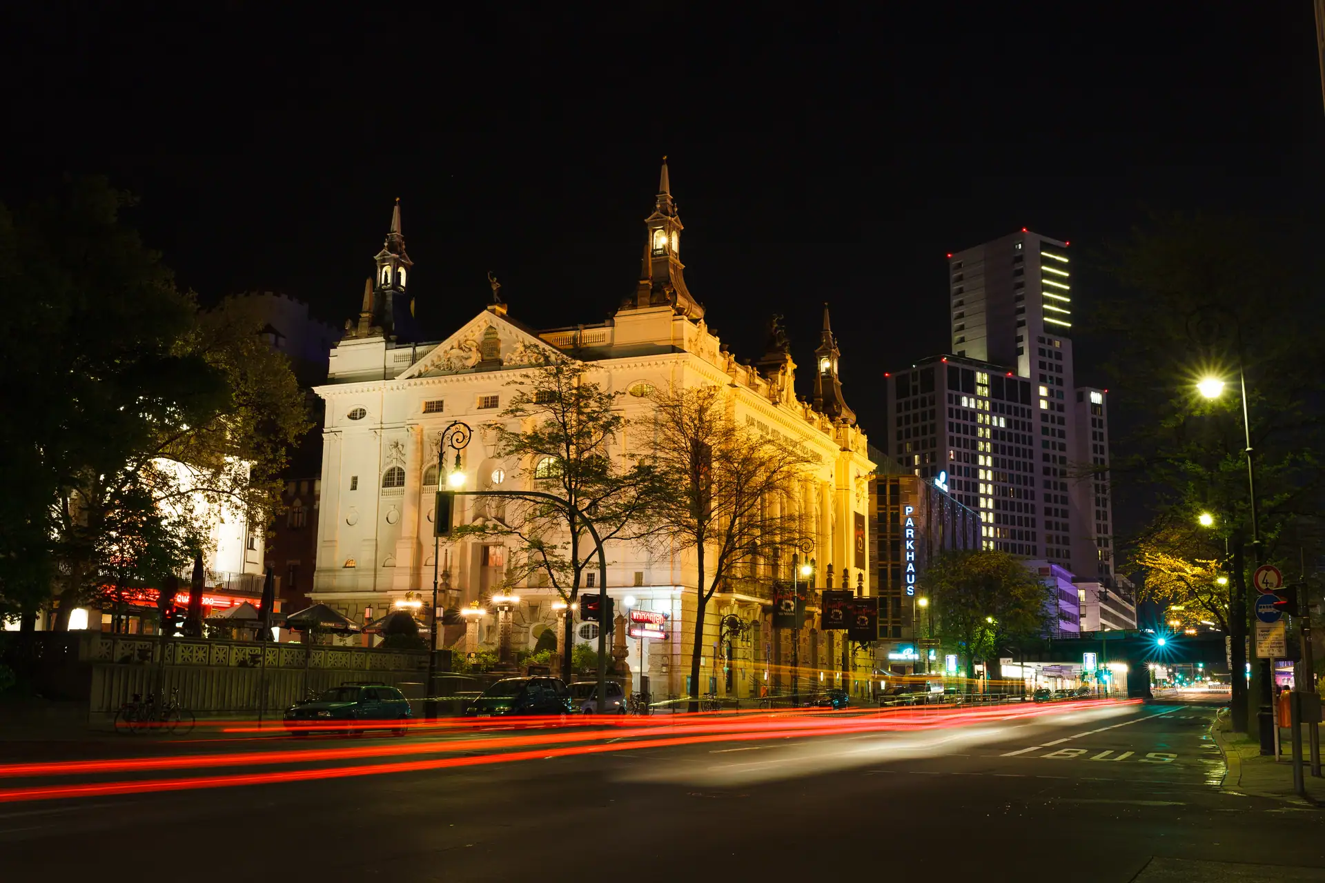 Berlin nightlife guide — Theater des Westens lit up on Kantstraße in Charlottenburg, car light trails on the road as the City West night starts