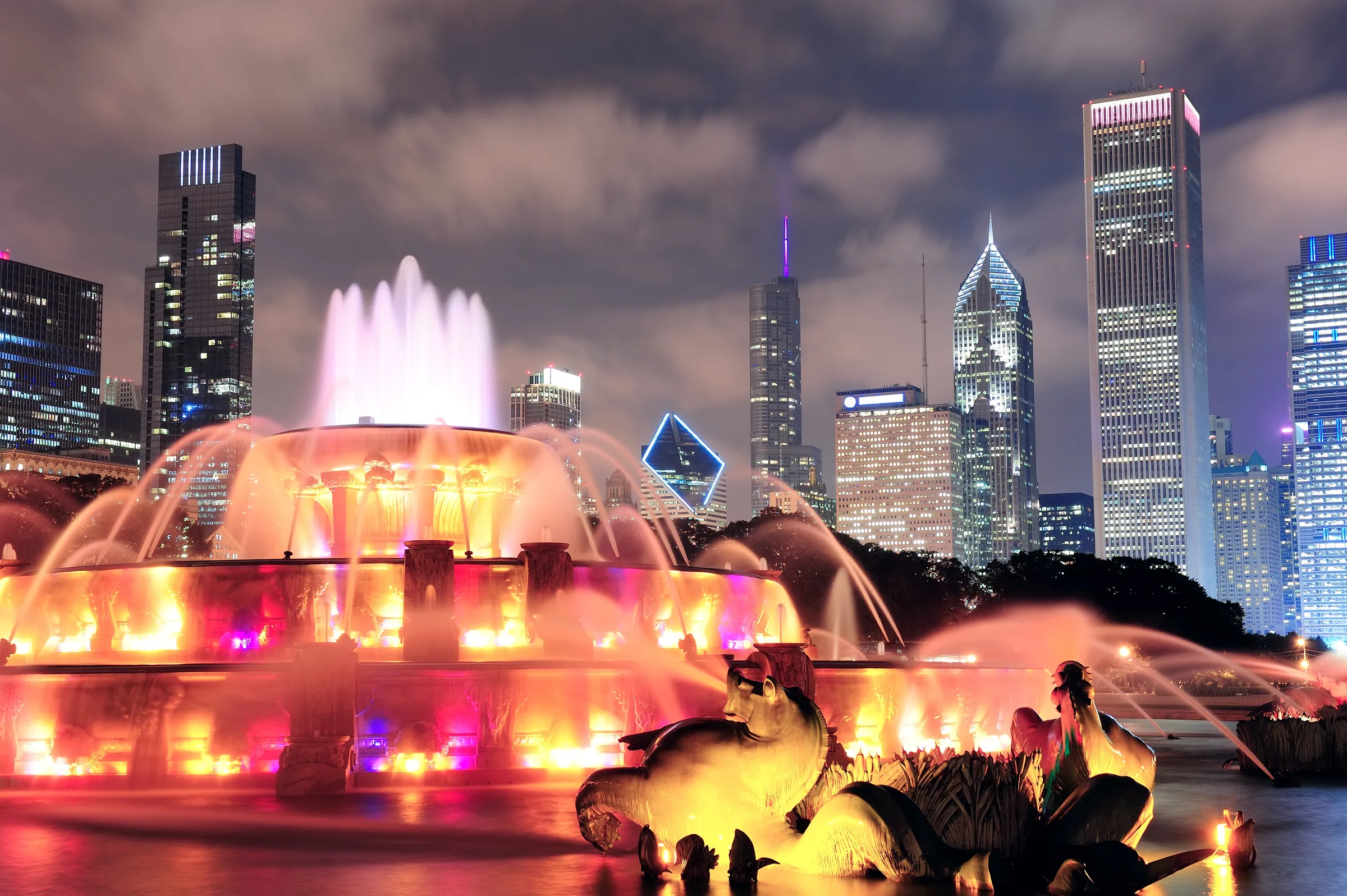 Best nights to go out in Chicago — Buckingham Fountain lit pink and gold at night in Grant Park, the Loop towers behind it, the view from the lakefront before the night moves to River North
