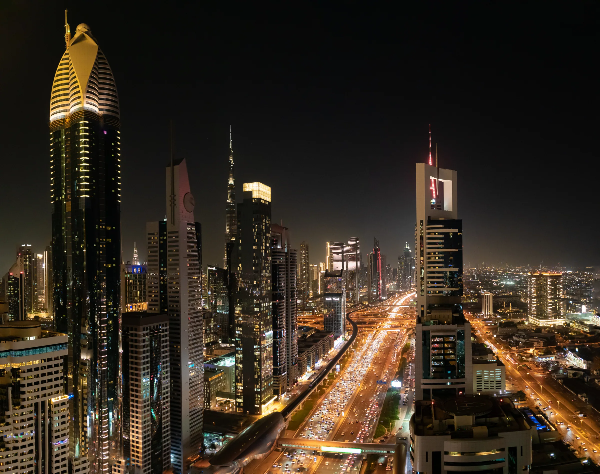 Dubai nightlife guide — the hotel towers of Sheikh Zayed Road lit at night above the traffic, the strip that holds most of the city's licensed bars and clubs