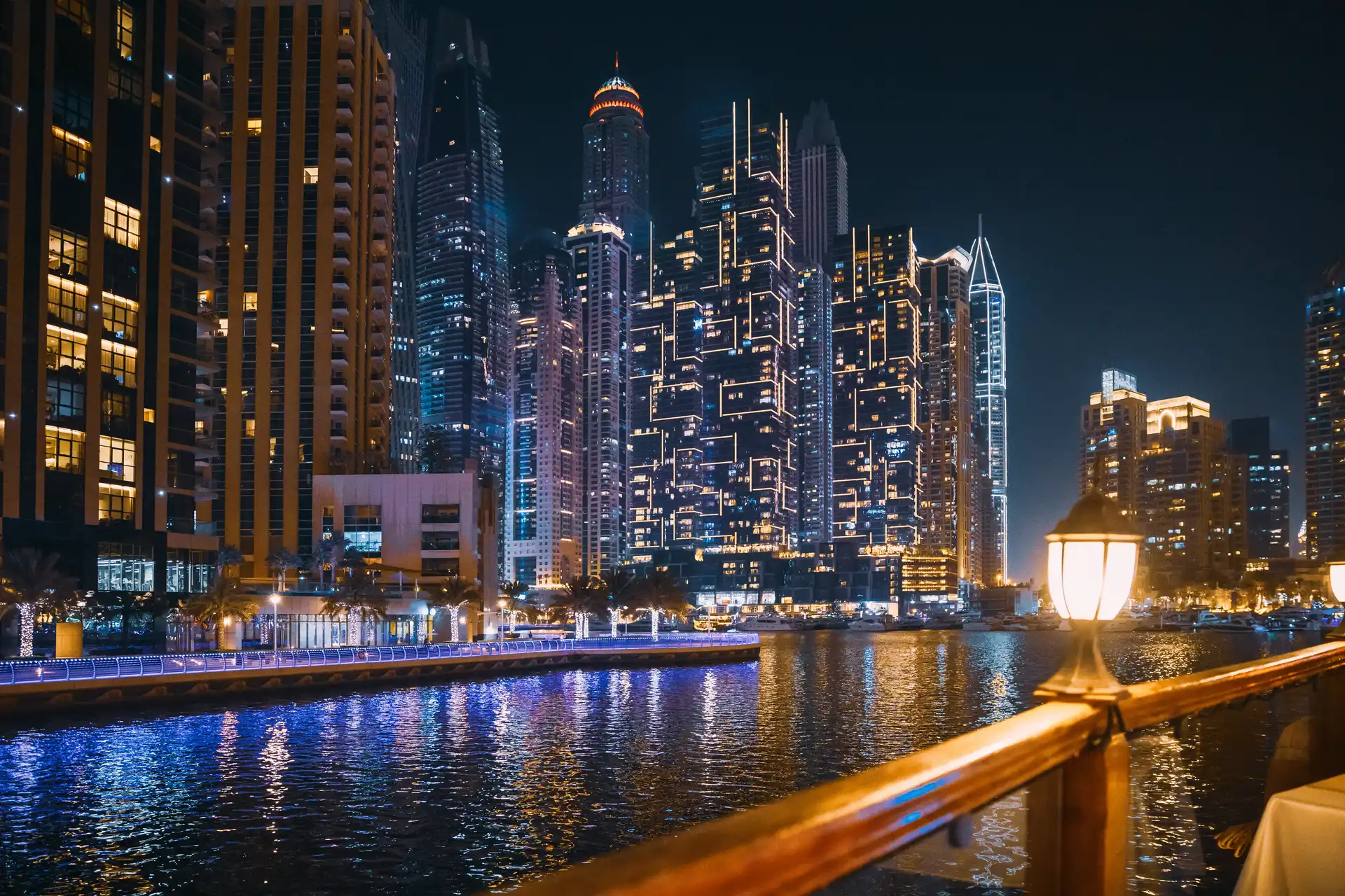 Dubai nightlife neighborhoods — the Dubai Marina towers lit at night above the marina walk, the beachside cluster that rates 4.61