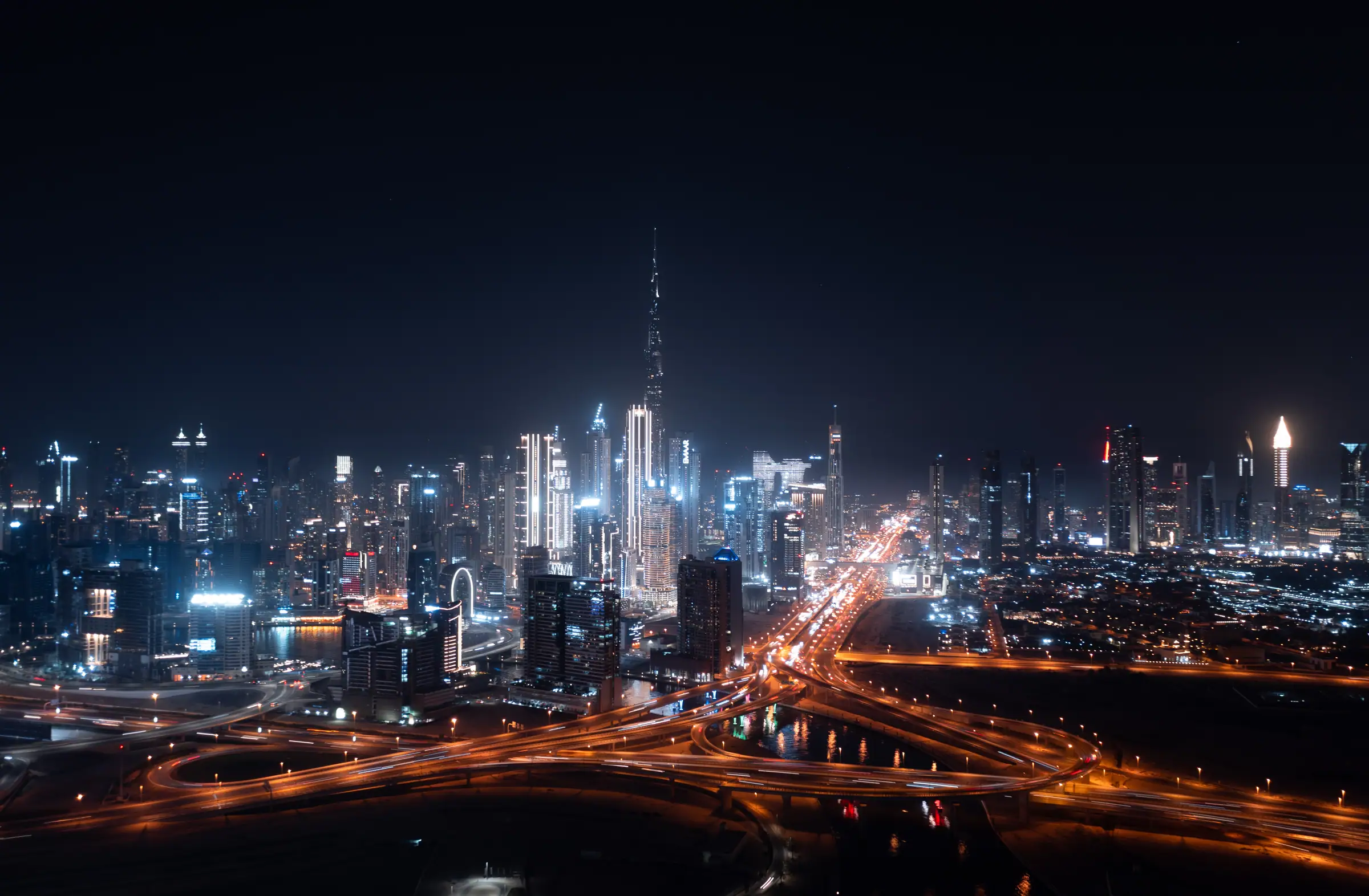 Clubs in Dubai — the Downtown and Business Bay towers and the Burj Khalifa lit at night above the Sheikh Zayed Road interchange, the strip that holds ten of the city's 26 revealed night clubs